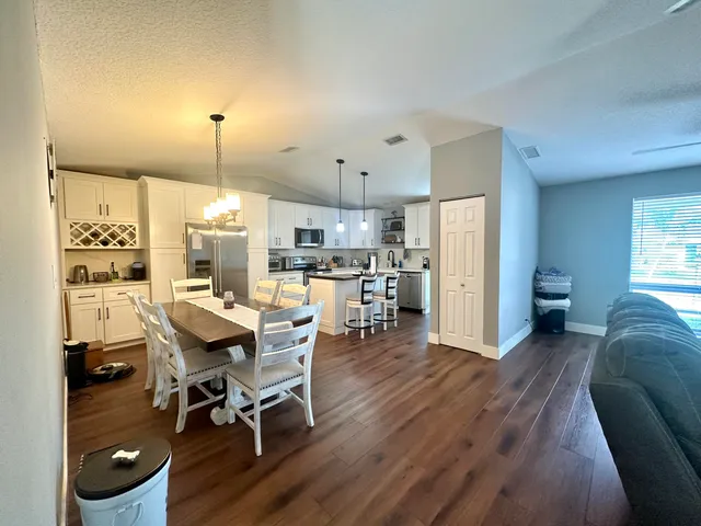a view of a dining room and a kitchen with a table chairs