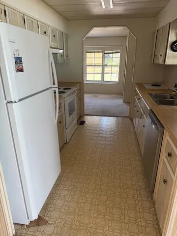 a view of a kitchen with refrigerator and white cabinets