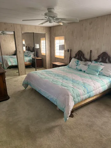 a bedroom with a bed a mirror on dresser and a chandelier