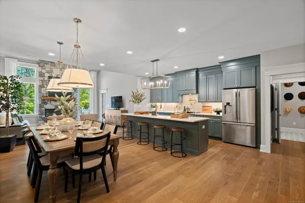 a kitchen with stainless steel appliances kitchen island granite countertop a table chairs and a refrigerator