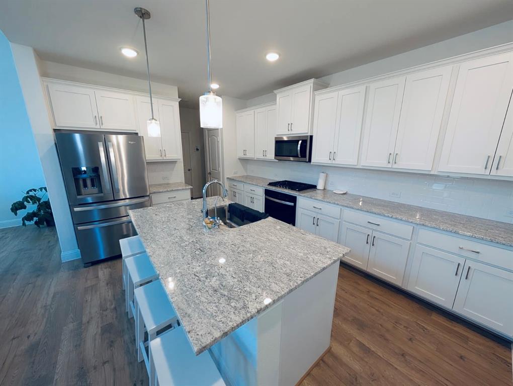 716 Blakelys Way Fate, TX 75189 - Photo 4 of 15 a kitchen with stainless steel appliances granite countertop a refrigerator a sink dishwasher a stove and white countertops with wooden floor