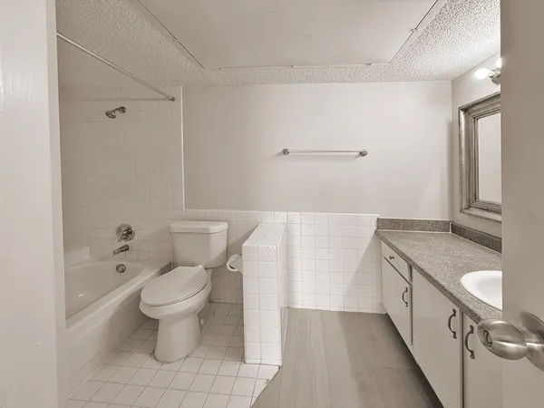 a bathroom with a granite countertop sink a toilet and shower