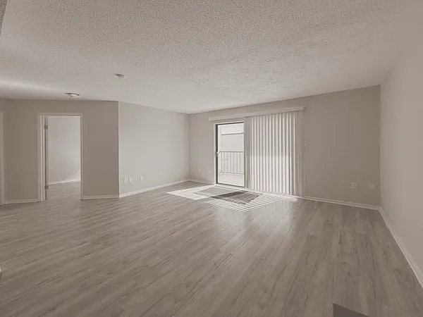 a view of an empty room with wooden floor and window