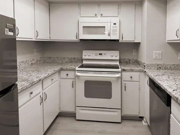 a kitchen with granite countertop white cabinets and white appliances