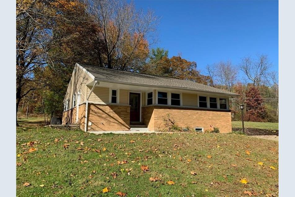 a view of house with backyard and trees in the background