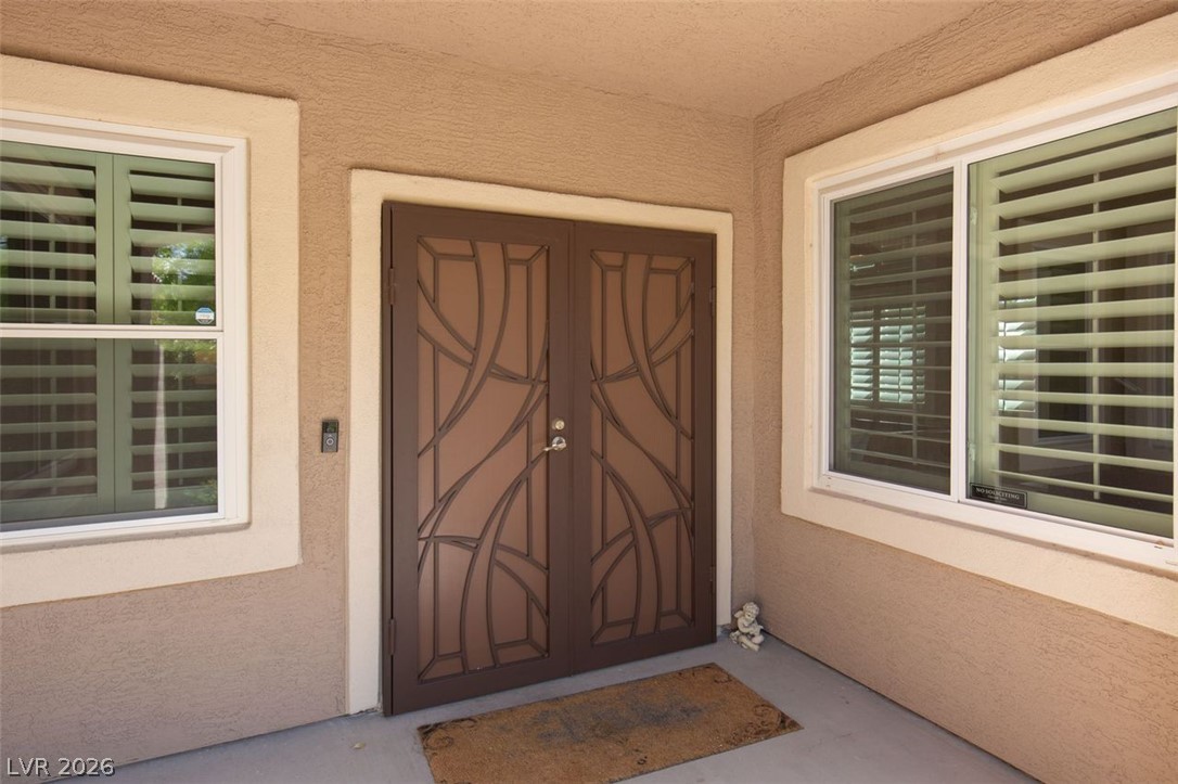 4670 Los Rancheros Avenue Las Vegas, NV 89129 - Photo 11 of 57 Double entry doors with decorative ironwork welcome guests under a sheltered concrete porch.
