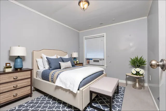 a bedroom with a bed and a potted plant on the dresser