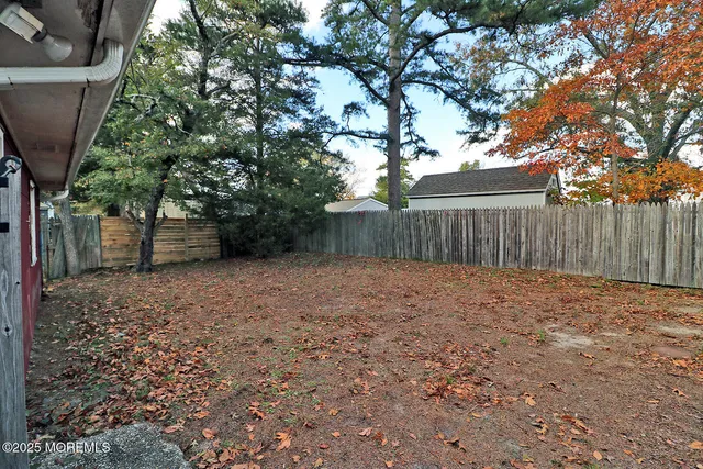 a view of a backyard with large trees and wooden fence