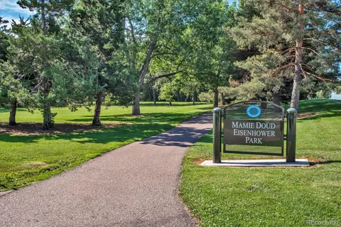 a view of a park that has a sign board large trees