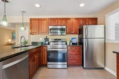 a kitchen with stainless steel appliances granite countertop a refrigerator a stove a sink and a microwave