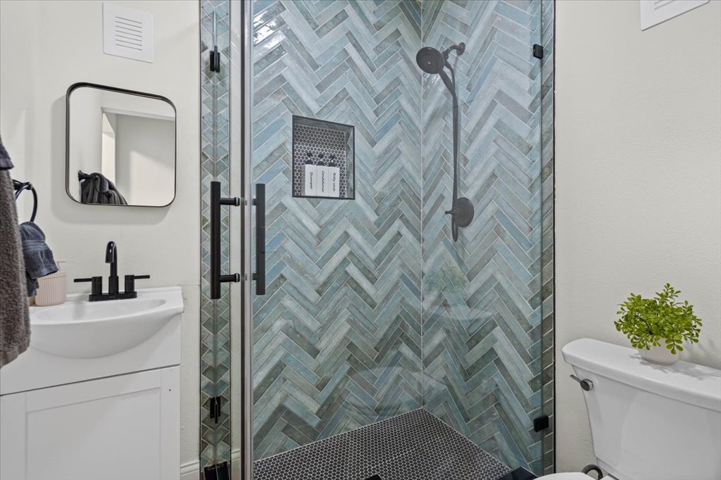 1201 Garden Street, Unit A Austin, TX 78702 - Photo 22 of 30 Glass-enclosed shower with herringbone pattern tile and black hardware