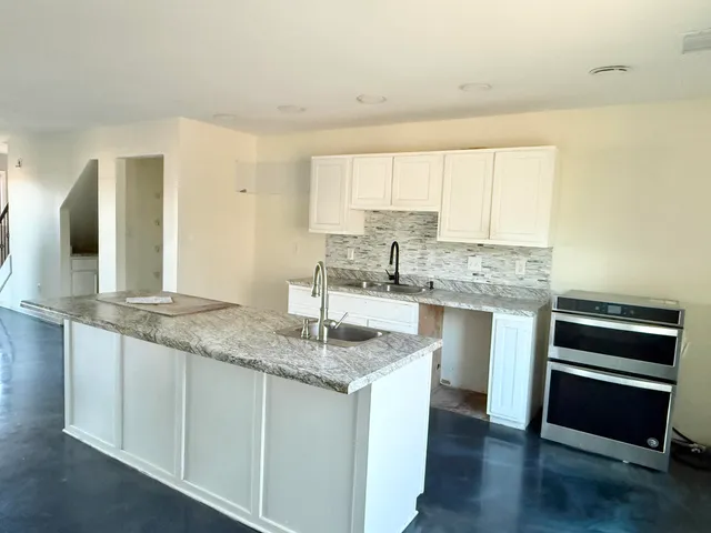 a living room with stainless steel appliances a wooden floor a large window and a wooden floor