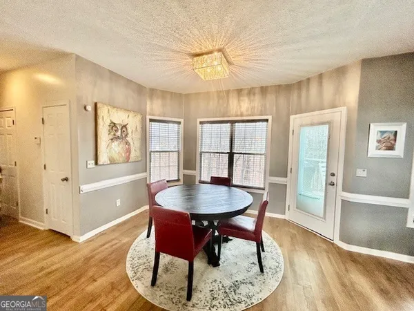 a dining room with wooden floor a chandelier a wooden table and chairs