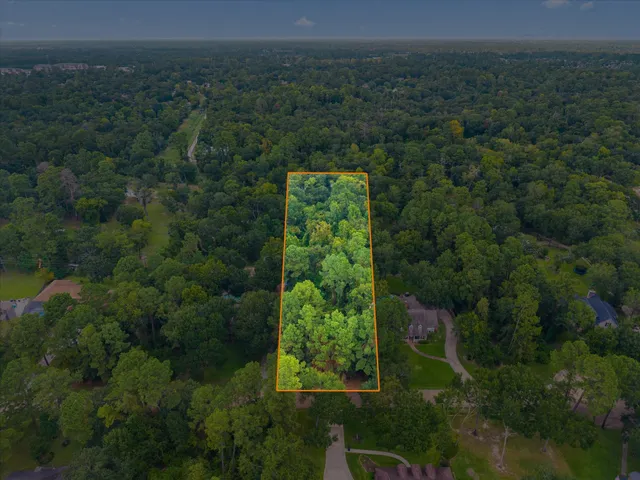 an aerial view of a residential houses with outdoor space and trees