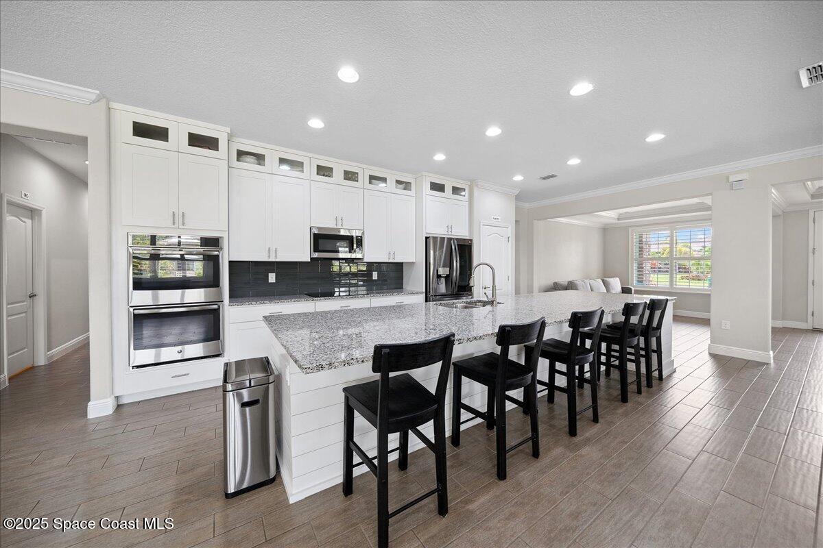 4357 Preservation Circle Melbourne, FL 32934 - Photo 12 of 56 a large kitchen with dining table chairs and refrigerator