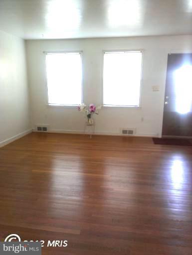 1615 Ramblewood Road Baltimore, MD 21239 - Photo 7 of 19 an empty room with wooden floor and windows