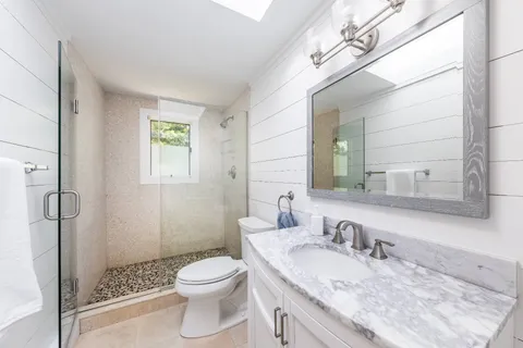 a bathroom with a granite countertop toilet a sink and a mirror