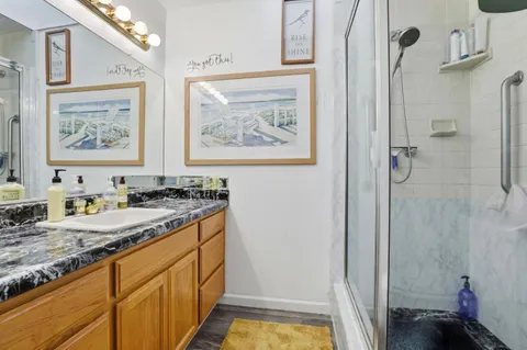 a bathroom with a granite countertop sink a mirror a vanity and a shower