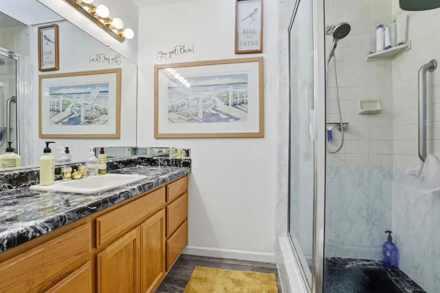 a bathroom with a granite countertop sink a mirror a vanity and a shower