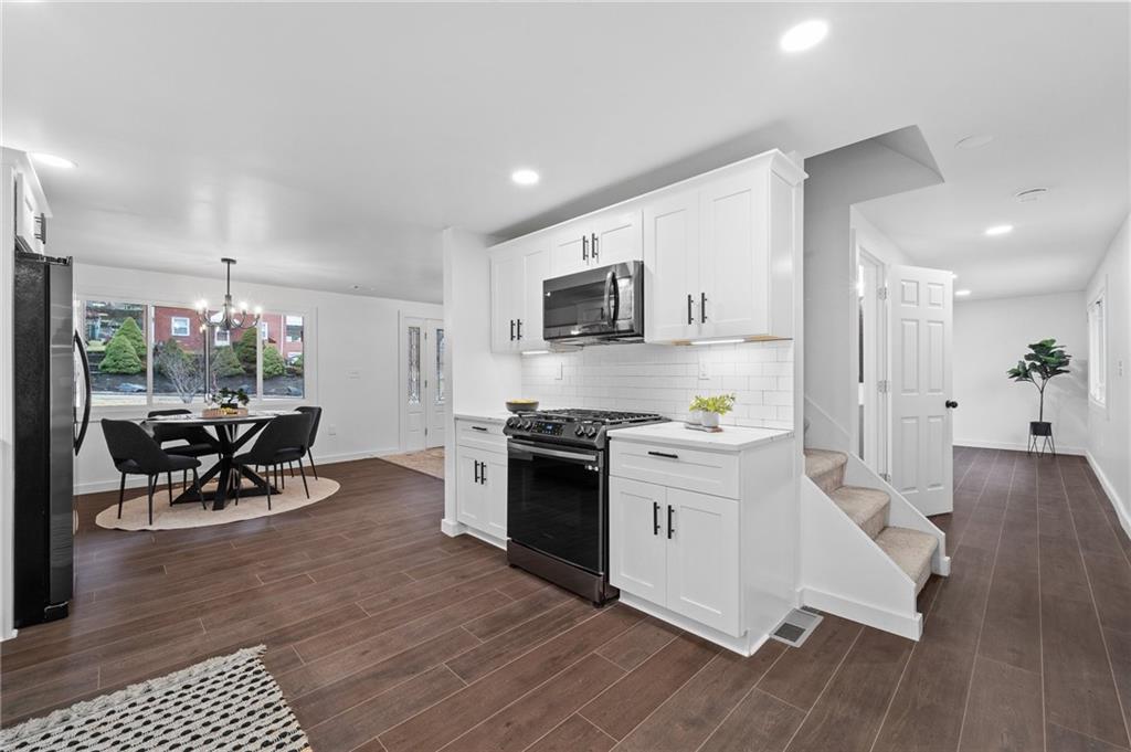 566 Kelso Road Pittsburgh, PA 15243 - Photo 15 of 40 a kitchen with stainless steel appliances a stove a sink a oven a dining table and chairs with wooden floor