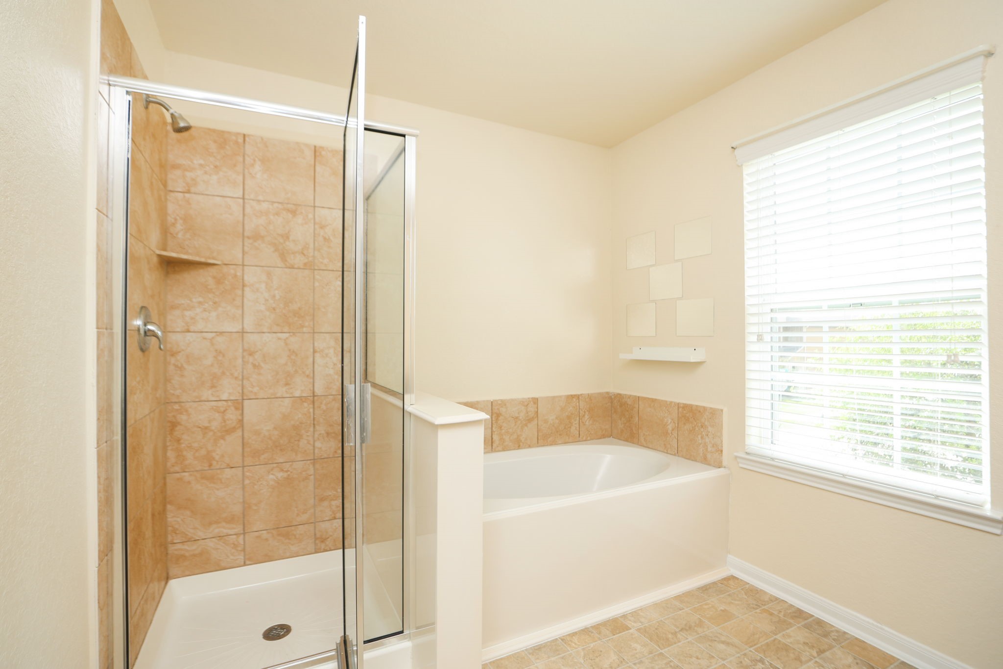 18402 Spruce Tree Line Trail Houston, TX 77084 - Photo 19 of 30 Bright bathroom featuring a tiled walk-in shower and a separate bathtub. Natural light fills the space through a large window with blinds.