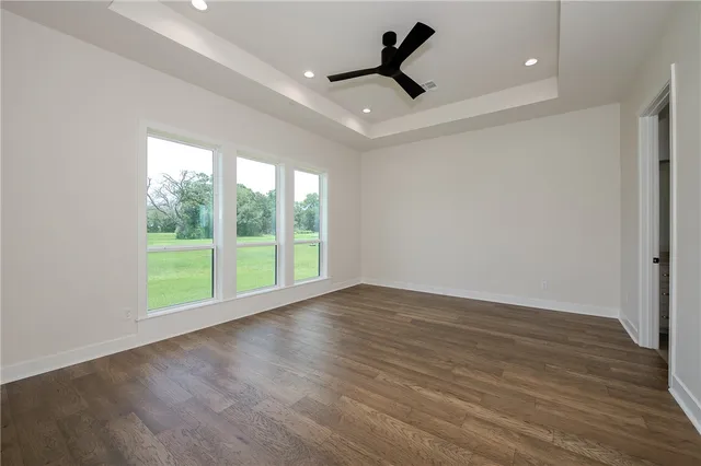 a view of empty room with wooden floor and fan