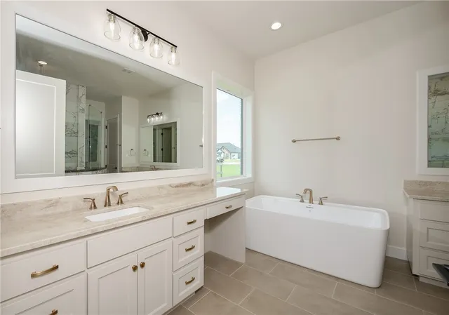 a bathroom with a sink double vanity granite tub and a mirror