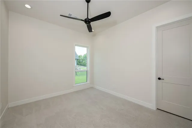 an empty room with a window and a ceiling fan