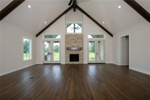 an empty room with wooden floor a fireplace and windows