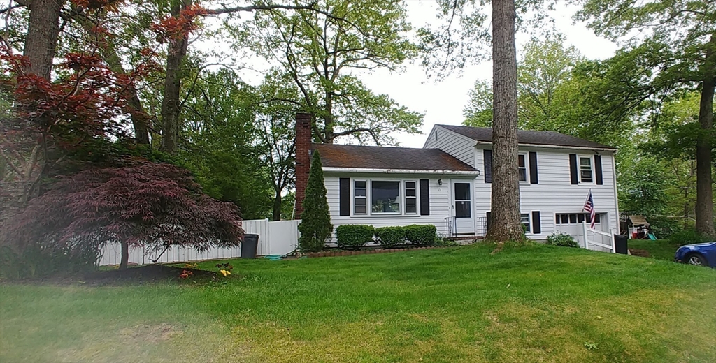 a front view of a house with a garden and trees