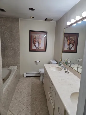 a bathroom with a double vanity sink a mirror a bathtub and toilet