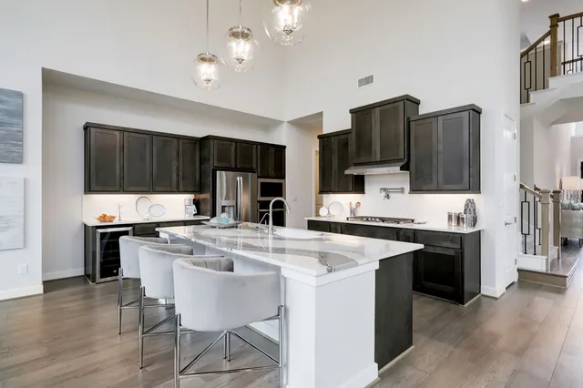 a kitchen with kitchen island granite countertop a sink cabinets a large window and stainless steel appliances