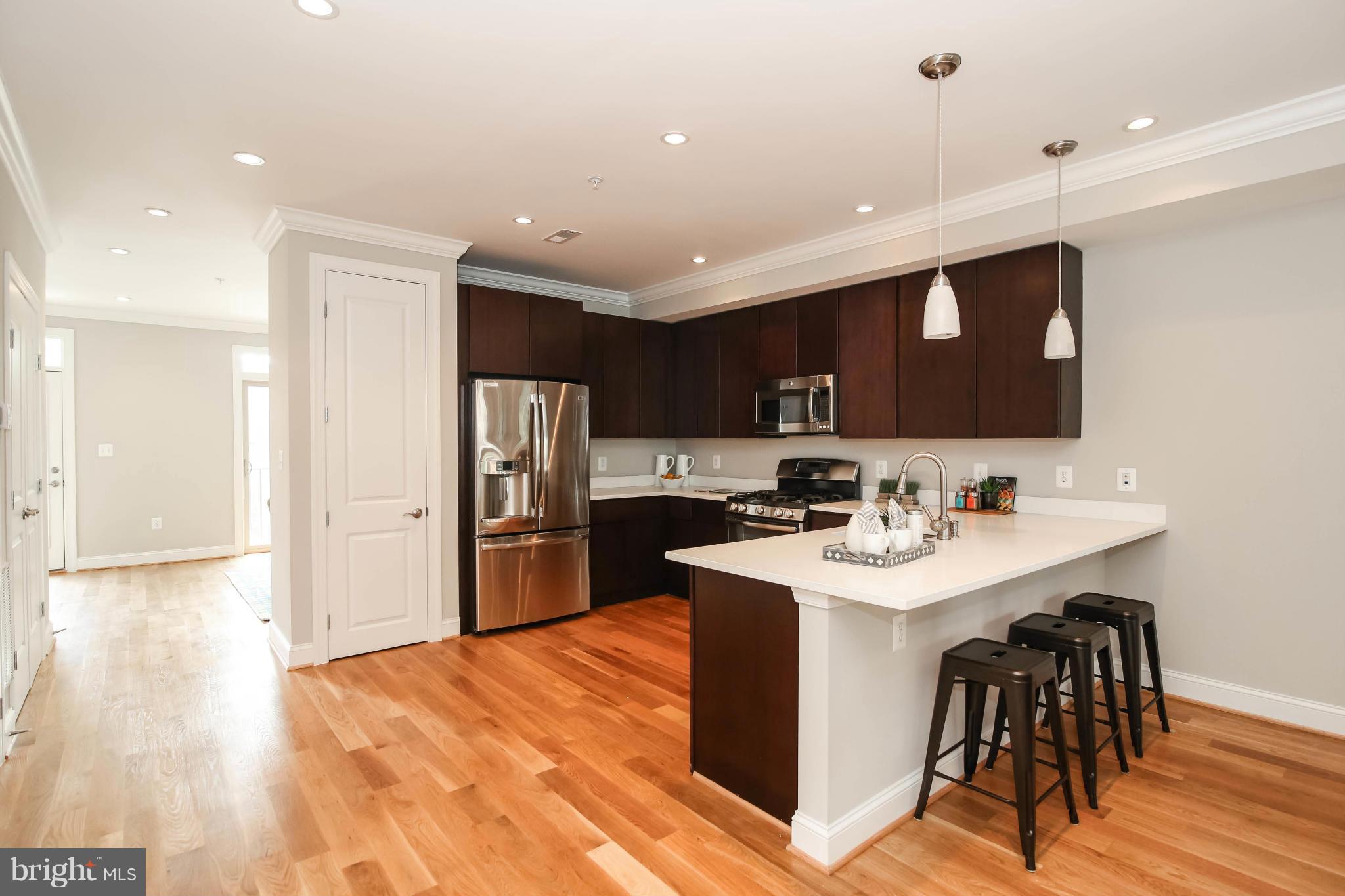 1131 5th Street Northeast, Unit 2 Washington, DC 20002 - Photo 7 of 27 a kitchen with stainless steel appliances granite countertop a sink a stove a refrigerator and island with wooden floor