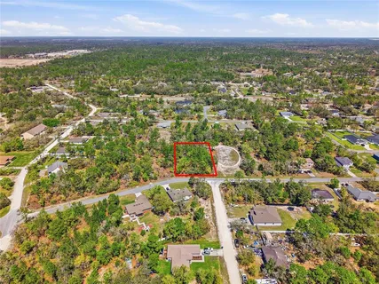 an aerial view of residential houses with outdoor space and trees