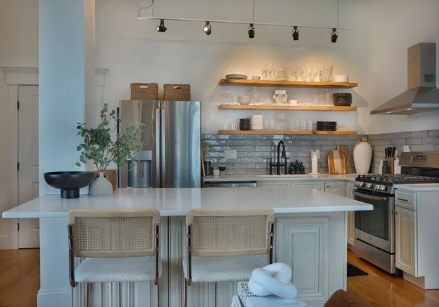 a kitchen with stainless steel appliances granite countertop a table chairs in it and wooden floors