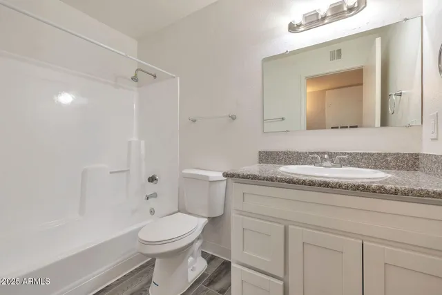 a bathroom with a granite countertop toilet sink and mirror