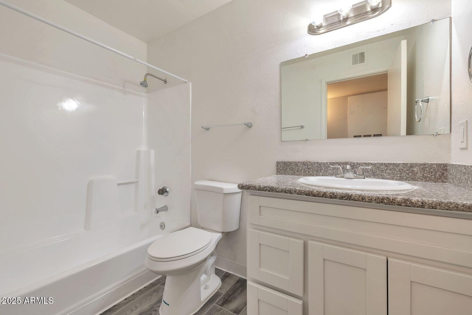 2216 East Eugie Terrace, Unit 207 Phoenix, AZ 85022 - Photo 5 of 7 a bathroom with a granite countertop toilet sink and mirror