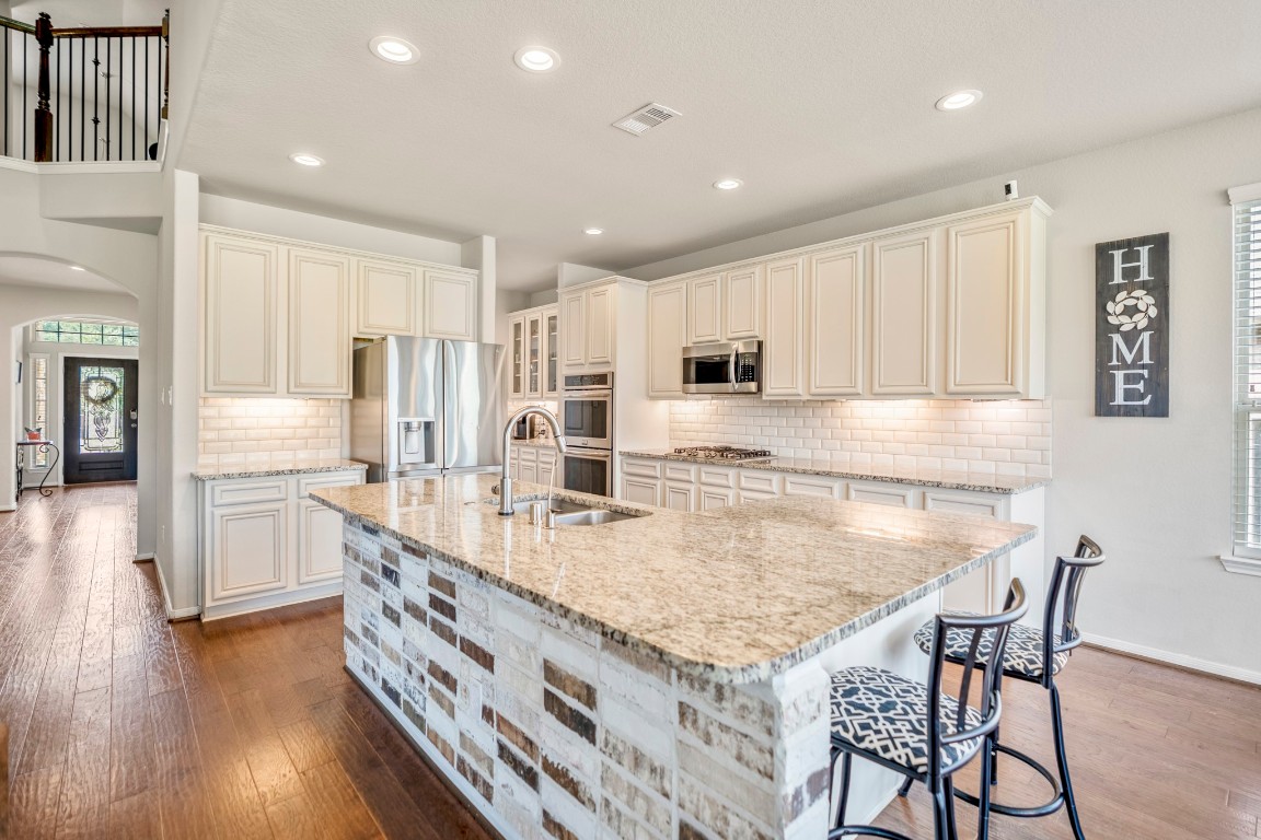 23006 Mulberry Tree Lane Spring, TX 77389 - Photo 14 of 50 The kitchen boasts granite counters, a brick-accented island with seating, stainless appliances, and abundant cabinetry for storage.