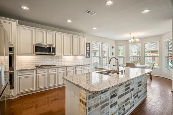 a large kitchen with granite countertop lots of counter space and wooden floor