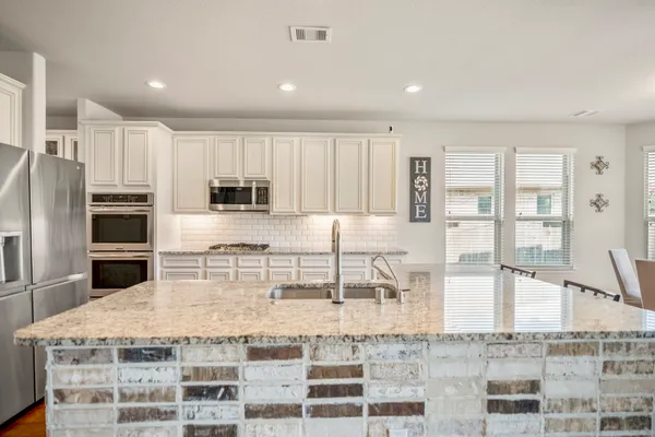 a kitchen with kitchen island granite countertop a large counter top stainless steel appliances and cabinets
