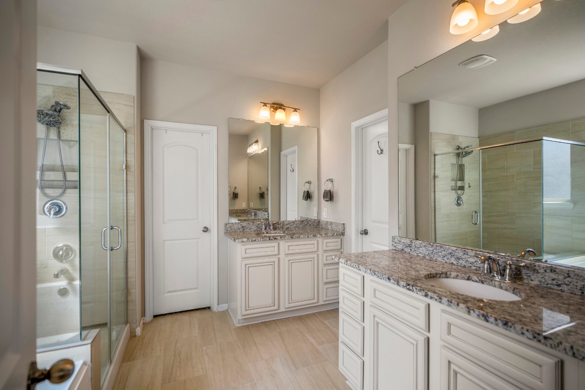 23006 Mulberry Tree Lane Spring, TX 77389 - Photo 23 of 50 The en-suite bath features separate granite vanities, a soaking tub, and a glass-enclosed shower for both comfort and convenience. The two doors ahead lead to the spacious walk-in closet and the private water closet.
