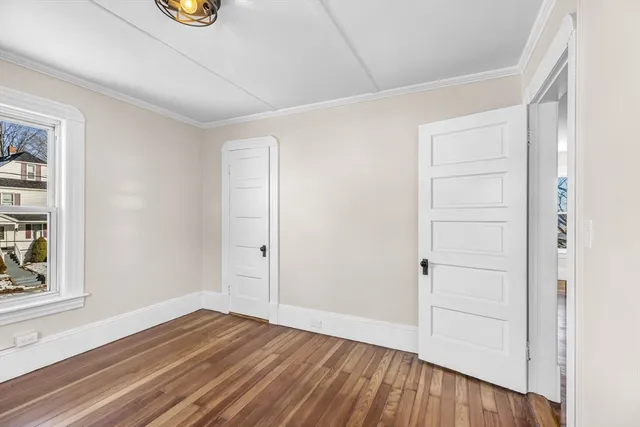 a view of an empty room with window and wooden floor