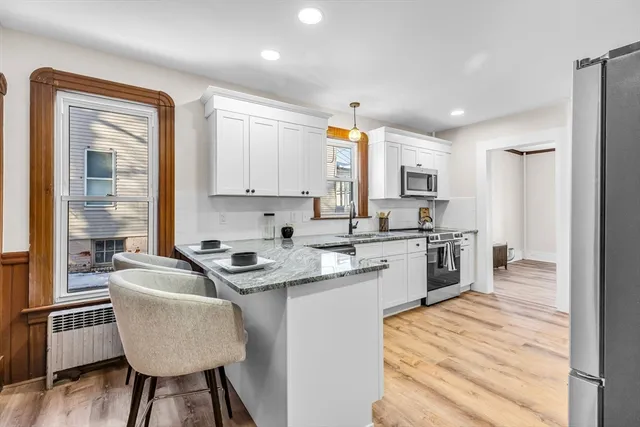 a kitchen with granite countertop kitchen island stainless steel appliances a stove a sink a refrigerator and cabinets