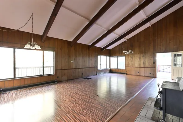 a view of an empty room with window and wooden floor