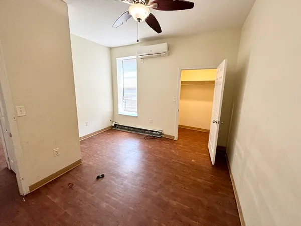an empty room with wooden floor cabinet and windows