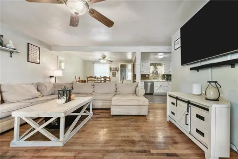 a living room with furniture a flat screen tv and kitchen view