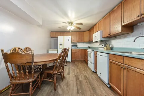 a kitchen with stainless steel appliances granite countertop a dining table chairs a refrigerator and cabinets