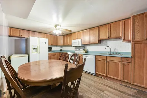 a kitchen with stainless steel appliances granite countertop a dining table chairs refrigerator a sink and dishwasher