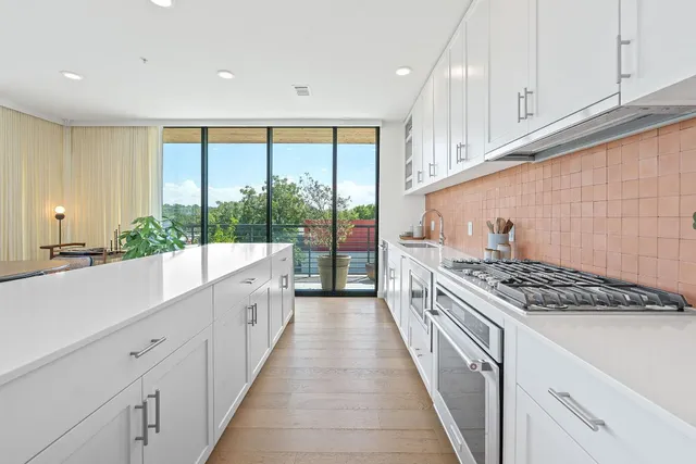 a large kitchen with stainless steel appliances granite countertop a stove a sink and white cabinets