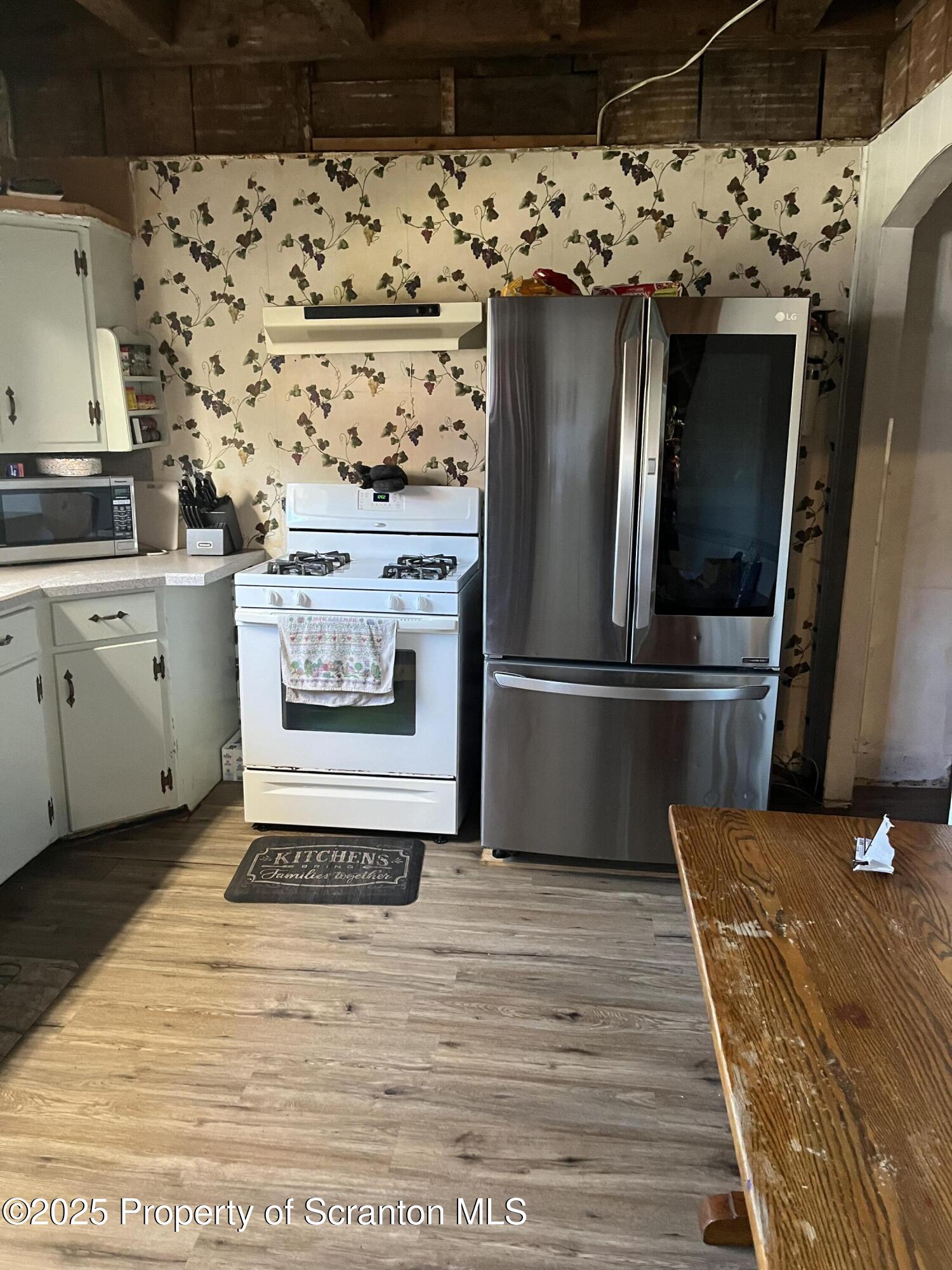 6666 Tingley Lake Road New Milford, PA 18834 - Photo 23 of 45 a view of a refrigerator in kitchen and an empty room with wooden floor